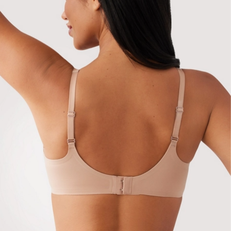 Woman wearing a beige bra against a plain background