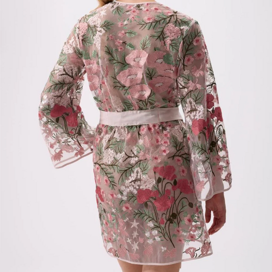 Woman wearing a floral dress with sheer sleeves on a white background