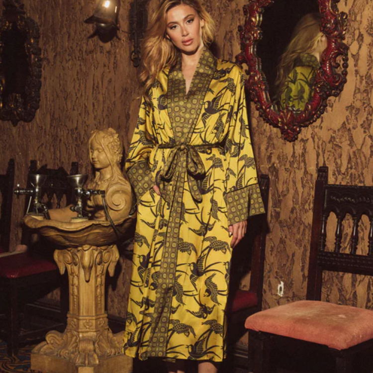 Woman in a patterned robe standing in an ornate room with decorative walls and furniture.