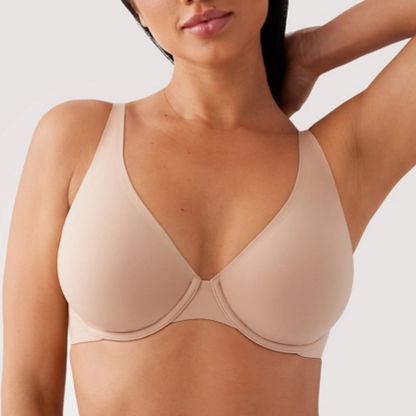 Woman wearing a beige bra against a plain background