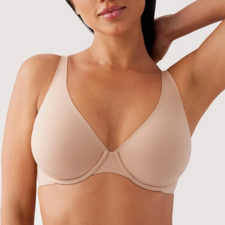 Woman wearing a beige bra against a plain background