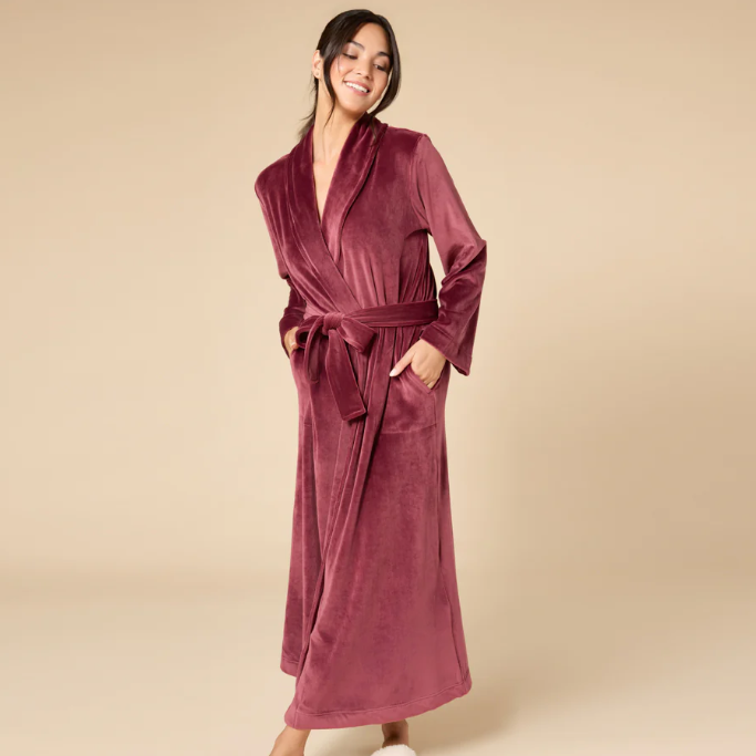 Woman wearing a burgundy robe against a beige background