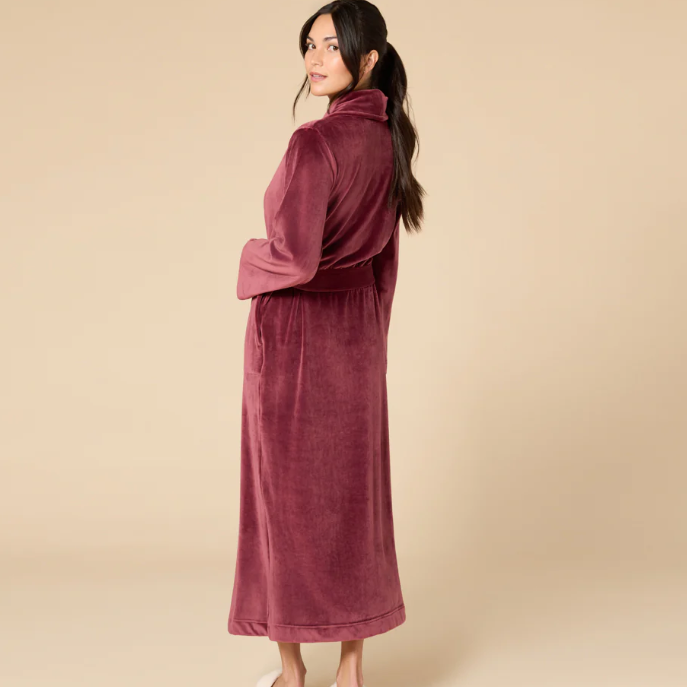 Woman wearing a burgundy robe against a beige background