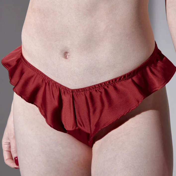Red ruffled underwear worn by a person on a gray background